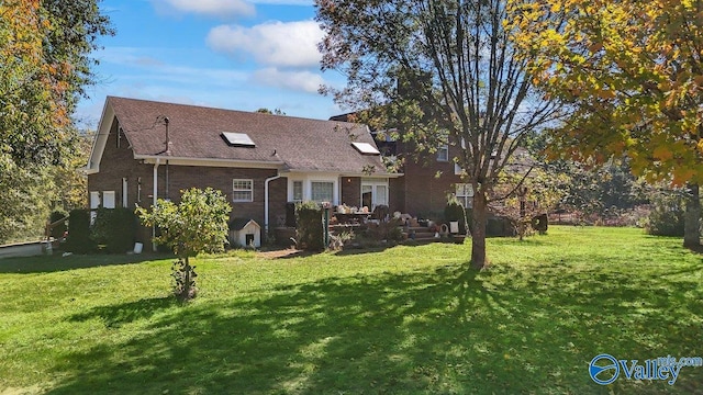 back of house featuring a lawn, a shingled roof, and brick siding