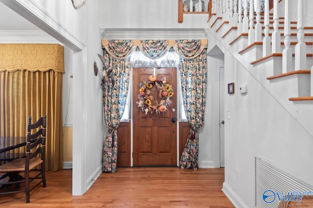 foyer entrance featuring crown molding, baseboards, and wood finished floors