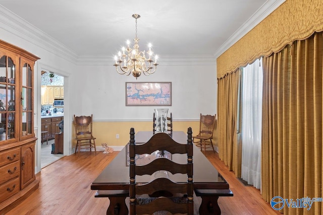 dining room featuring an inviting chandelier, crown molding, and light wood-style floors