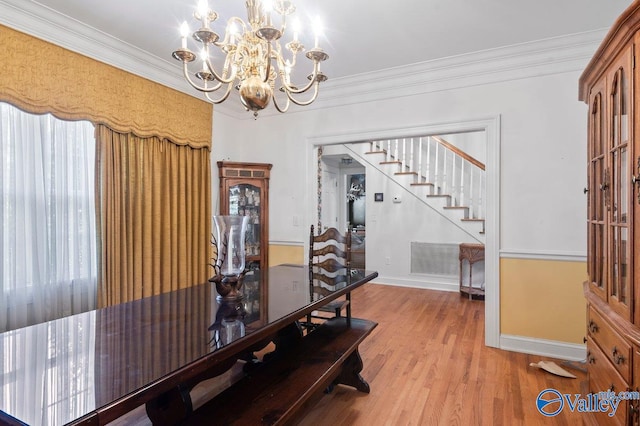 dining room with crown molding, a notable chandelier, light wood finished floors, stairs, and baseboards