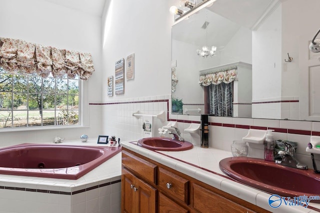 bathroom featuring vanity, a chandelier, and a relaxing tiled tub