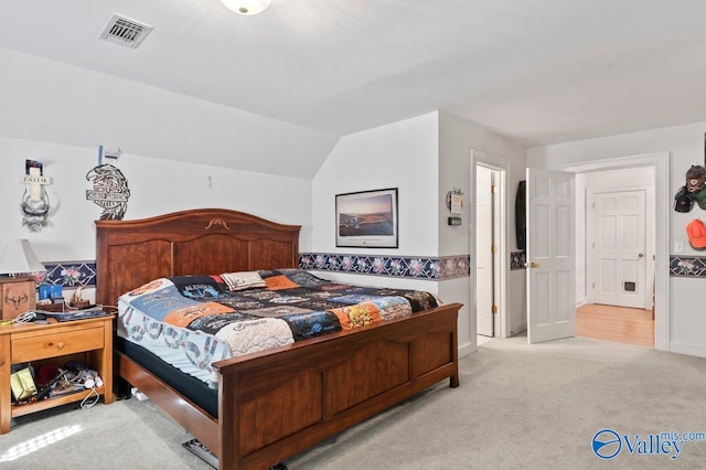 bedroom with vaulted ceiling and light colored carpet