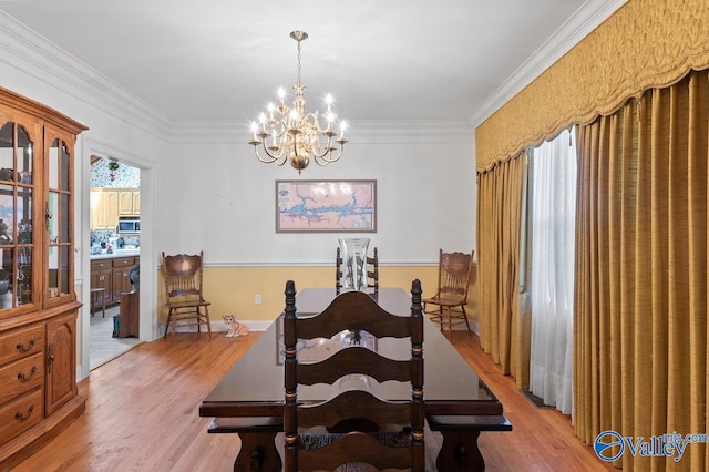 dining area featuring light hardwood / wood-style floors, ornamental molding, and a chandelier