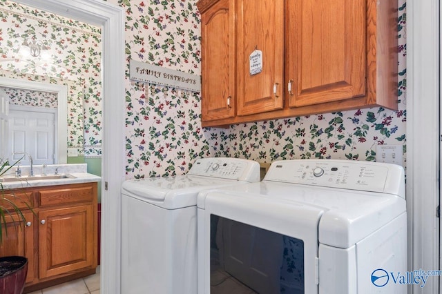 clothes washing area with washing machine and dryer, cabinet space, a sink, light tile patterned floors, and wallpapered walls