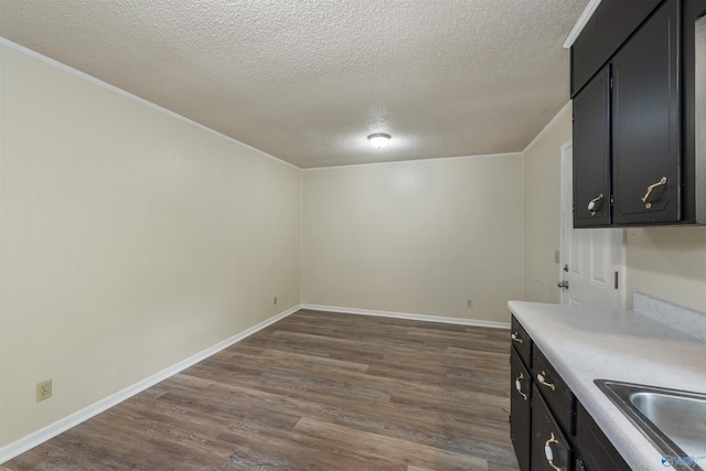 kitchen with dark wood-type flooring, crown molding, sink, and a textured ceiling