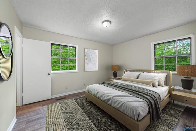 bedroom with light hardwood / wood-style floors and a textured ceiling