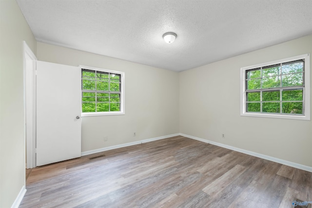 spare room with light hardwood / wood-style floors and a textured ceiling