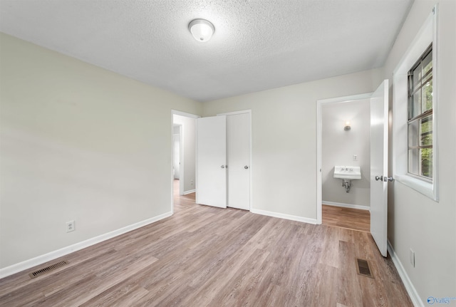 unfurnished bedroom featuring light wood-type flooring and a textured ceiling