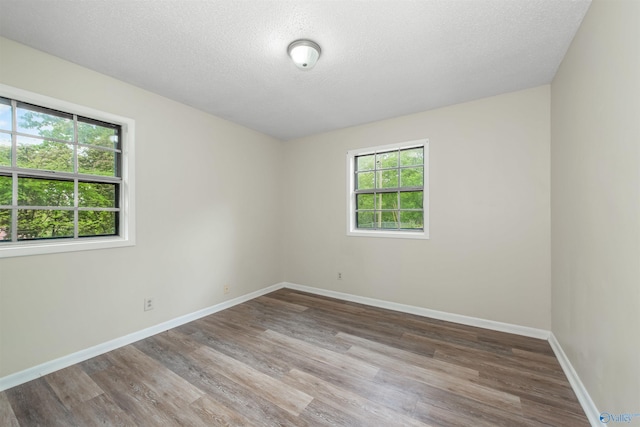 unfurnished room with hardwood / wood-style flooring, a wealth of natural light, and a textured ceiling