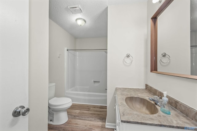 full bathroom featuring a textured ceiling, toilet, vanity,  shower combination, and hardwood / wood-style flooring