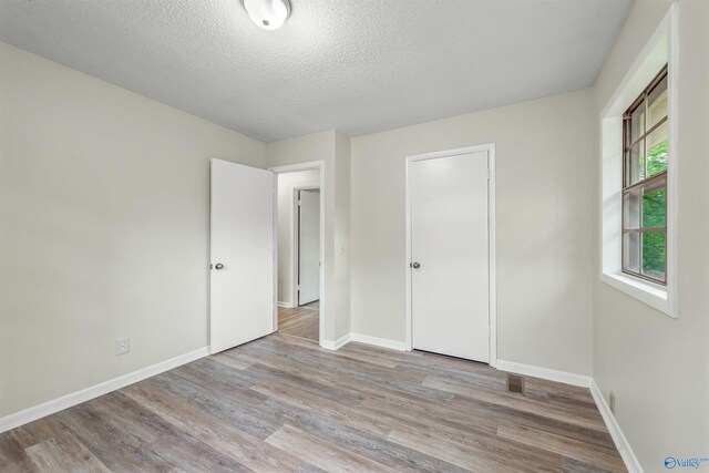 unfurnished bedroom with a closet, a textured ceiling, and hardwood / wood-style floors