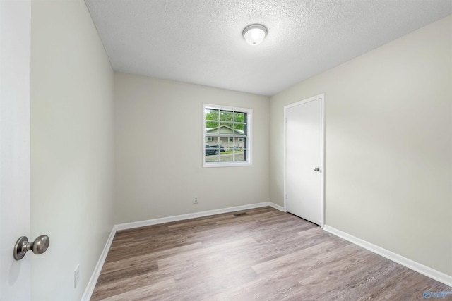 unfurnished room featuring light hardwood / wood-style floors and a textured ceiling