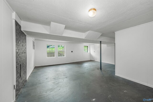 basement featuring brick wall and a textured ceiling