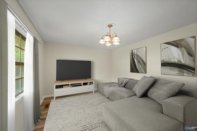 living room featuring hardwood / wood-style flooring, a textured ceiling, and a chandelier