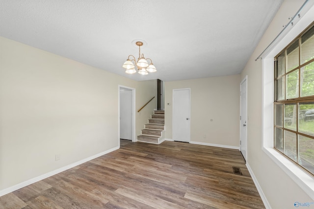 unfurnished living room with a notable chandelier and hardwood / wood-style floors