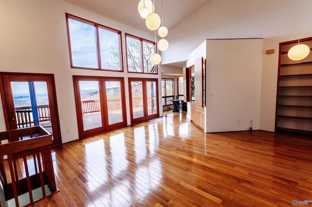 living area with high vaulted ceiling, french doors, and hardwood / wood-style flooring