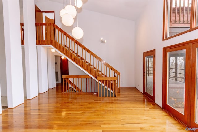 entrance foyer with stairs, a high ceiling, and wood finished floors