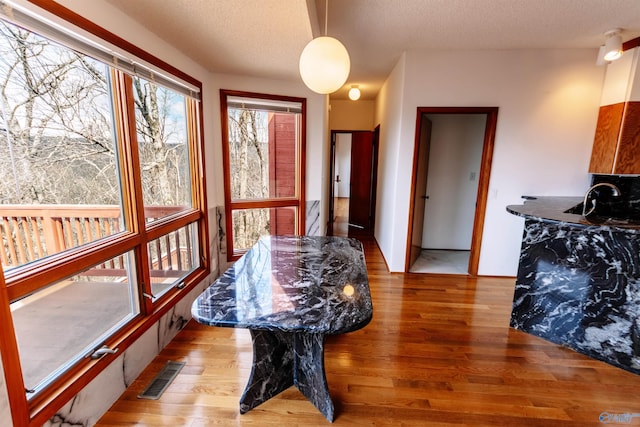 dining space featuring light wood finished floors, visible vents, and a textured ceiling