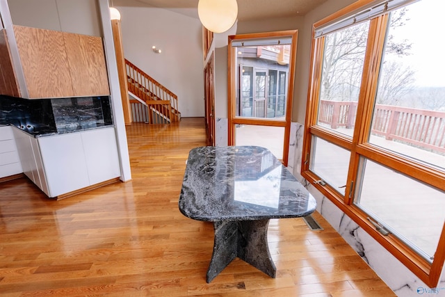 dining space featuring visible vents, light wood finished floors, and stairs