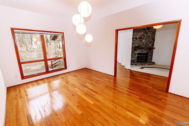 unfurnished dining area featuring wood-type flooring and a stone fireplace