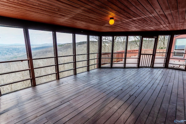 unfurnished sunroom with wooden ceiling, plenty of natural light, and a mountain view