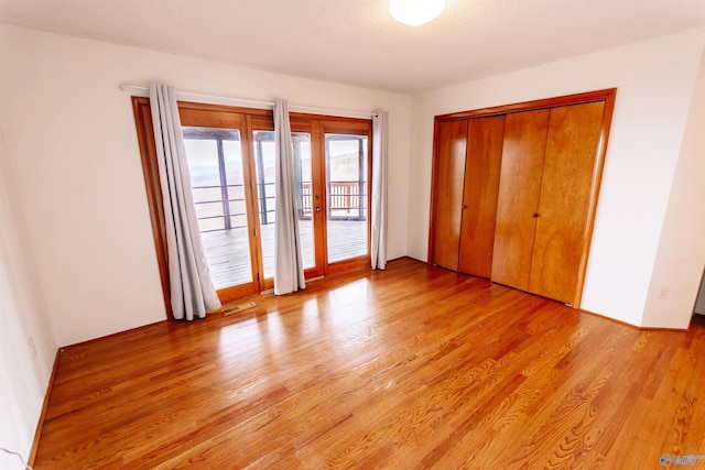 unfurnished bedroom featuring light wood-style floors, access to outside, a closet, and visible vents