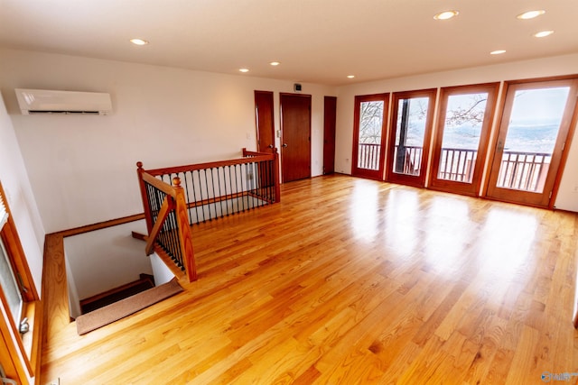 empty room with light wood-type flooring, an AC wall unit, and recessed lighting