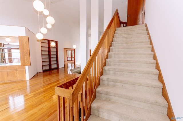 stairs featuring a high ceiling and wood finished floors