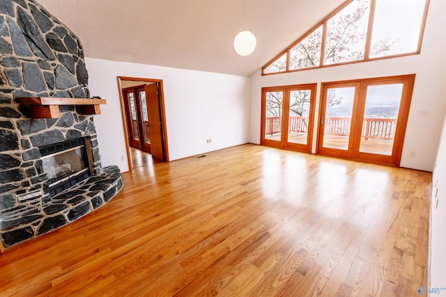 unfurnished living room with a textured ceiling, a fireplace, high vaulted ceiling, and wood finished floors