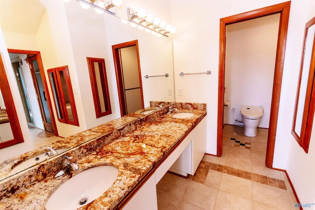 bathroom with toilet, double vanity, and a sink