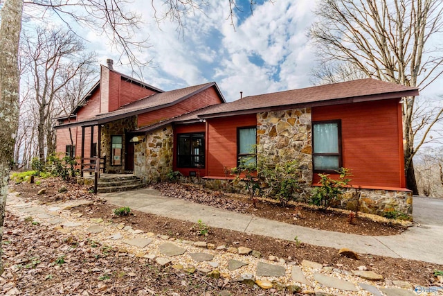 view of front of property with stone siding and a chimney