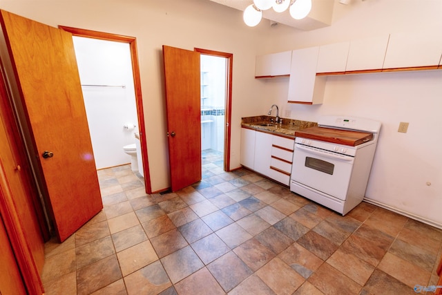 kitchen featuring electric stove, stone finish floor, a sink, and white cabinets