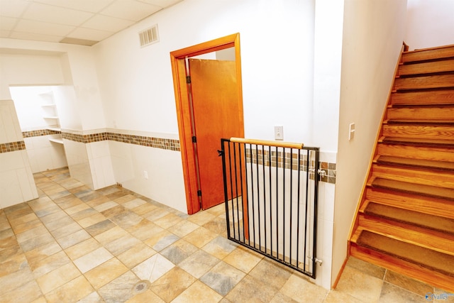 hallway featuring visible vents, stairway, and a drop ceiling