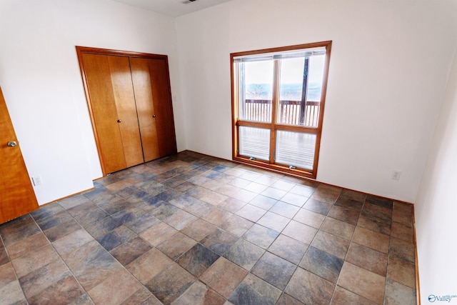 unfurnished bedroom with a closet and stone finish floor