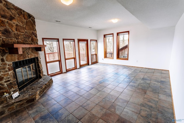 unfurnished living room with a stone fireplace and a textured ceiling