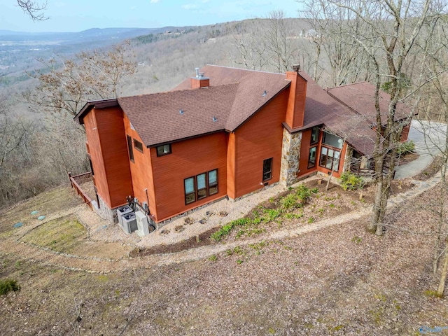 exterior space featuring roof with shingles, a chimney, and a mountain view