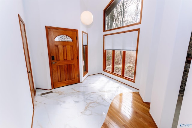 foyer featuring marble finish floor, visible vents, and a high ceiling