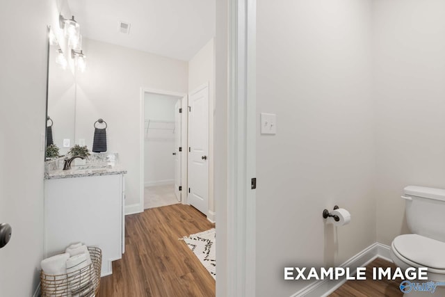 bathroom with toilet, baseboards, visible vents, wood finished floors, and vanity