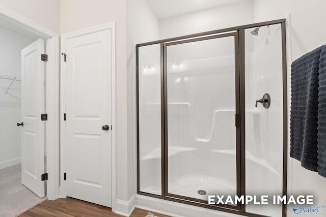 bathroom featuring baseboards, wood finished floors, and a stall shower