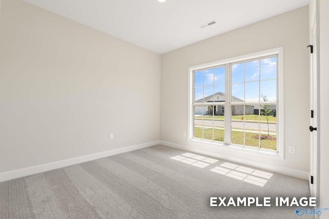unfurnished room with visible vents, plenty of natural light, baseboards, and carpet