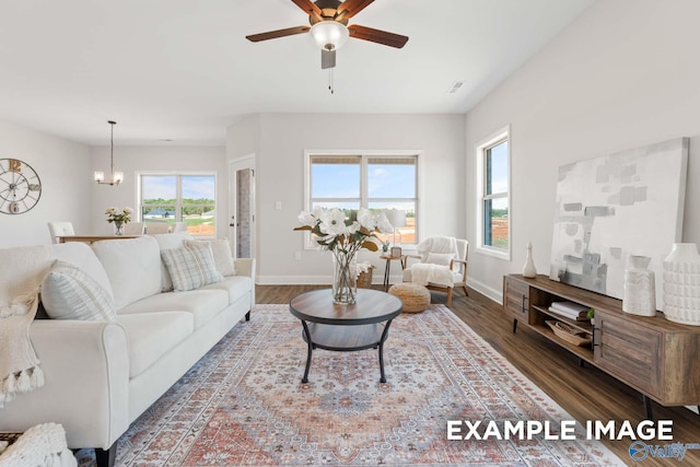 living room featuring wood finished floors, baseboards, and ceiling fan with notable chandelier