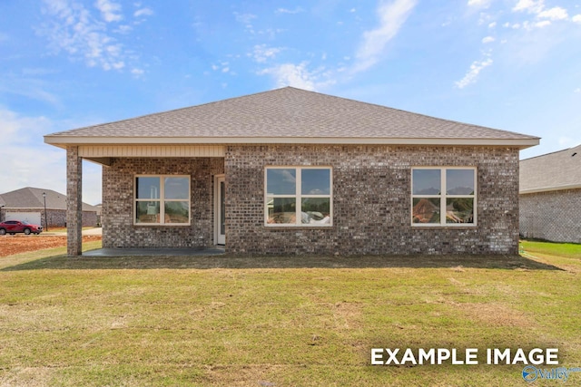 back of house with brick siding, a lawn, a patio, and roof with shingles