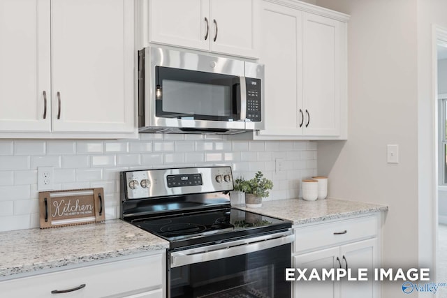 kitchen with stainless steel appliances, decorative backsplash, white cabinetry, and light stone counters