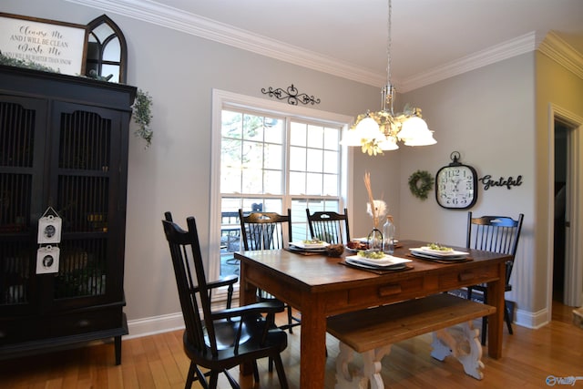 dining space with hardwood / wood-style flooring, crown molding, and a chandelier