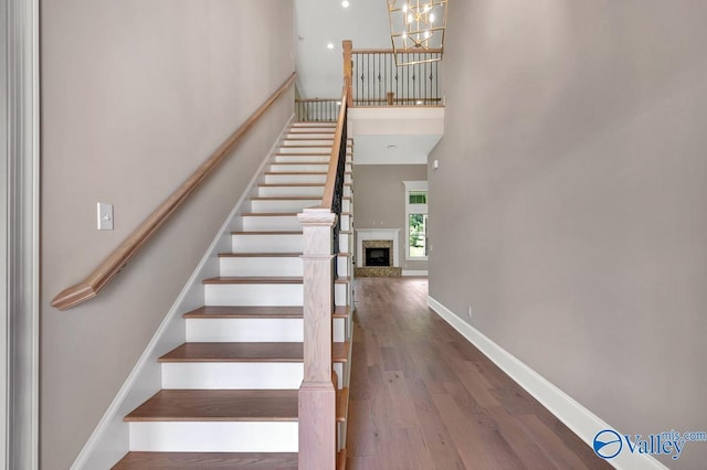 stairs featuring hardwood / wood-style floors, a chandelier, and a high ceiling