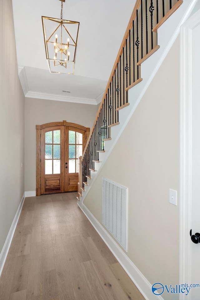 entryway featuring french doors, an inviting chandelier, crown molding, and light hardwood / wood-style floors