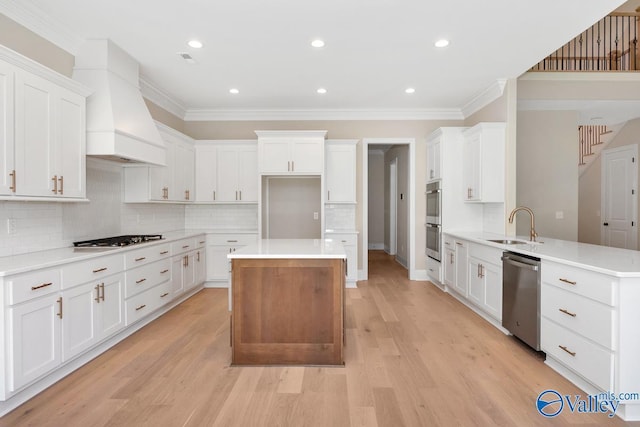 kitchen featuring sink, kitchen peninsula, custom range hood, stainless steel appliances, and white cabinets