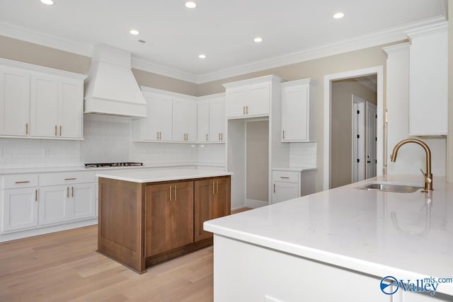 kitchen featuring white cabinetry, sink, gas stovetop, and premium range hood