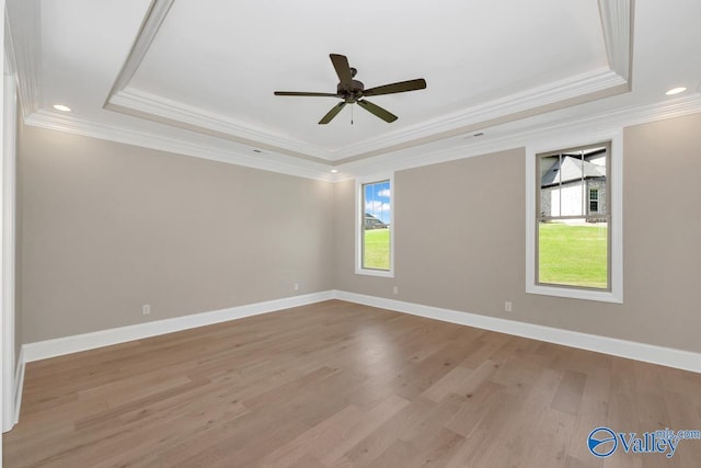 spare room with crown molding, a raised ceiling, ceiling fan, and light wood-type flooring