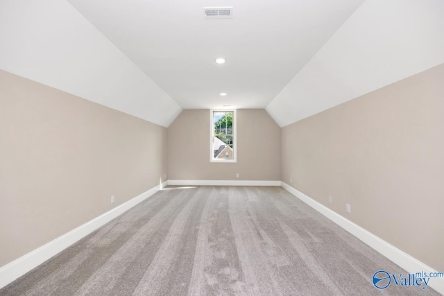 bonus room with vaulted ceiling and light colored carpet